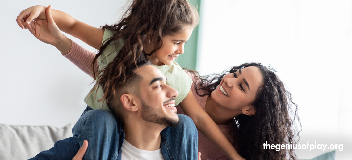 parents and young daughter smiling and playing in a living room at home