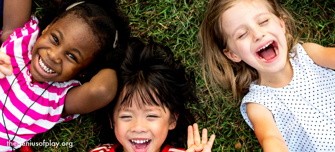 group of elementary aged kids lying on the grass outside and smiling